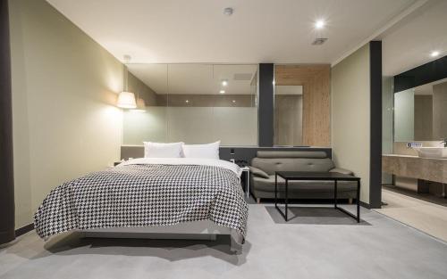 a bedroom with a bed and a bathroom with a sink at Hotel AND in Suwon
