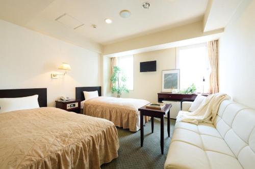a hotel room with two beds and a couch at Hotel Sho Sapporo - Vacation STAY 61183v in Sapporo
