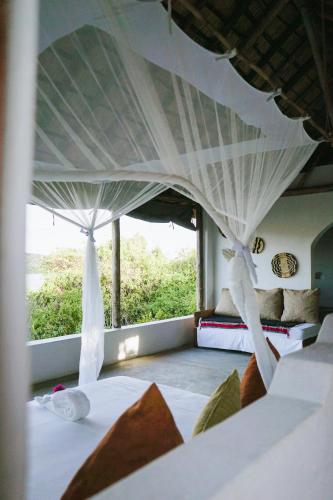 a bedroom with a canopy bed with a large window at Zua Safari Lodge in Chikwawa