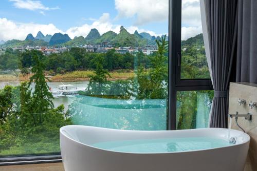 a bath tub in front of a window with a view at Lux CABINS一方山水 in Guilin