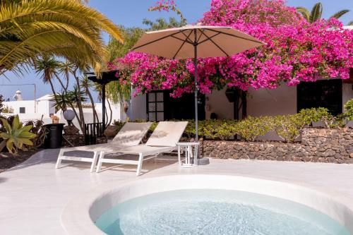 a pool with an umbrella and two chairs and a chair sidx sidx sidx at Finca Malvasia Rural Estate & Vineyard in Tías