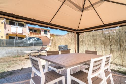 a wooden table and chairs under an umbrella at Un giardino sul mare in Budoni