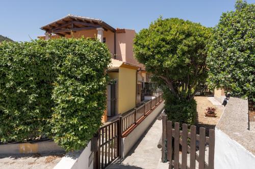 a fence with trees in front of a house at Un giardino sul mare in Budoni