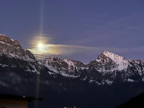 a sun setting over a mountain range with snow covered mountains at Large vacation home with mountain views in Quarten