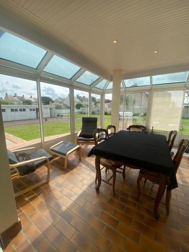 une pièce avec une table, des chaises et des fenêtres dans l'établissement Grande Maison familiale 50m de la plage - Le nid d'Asnelles, à Asnelles
