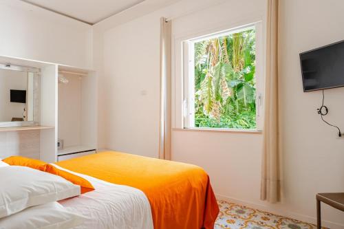 a bedroom with a bed with an orange blanket and a window at Villa Alimede in Positano