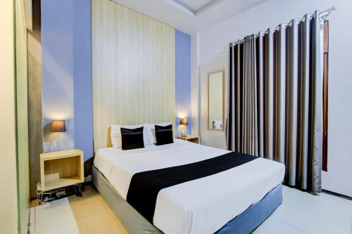 a bedroom with a large white bed with blue walls at Hotel O Tegal near near Pacific Mall Tegal formerly Hugo Suites Family in Tegal