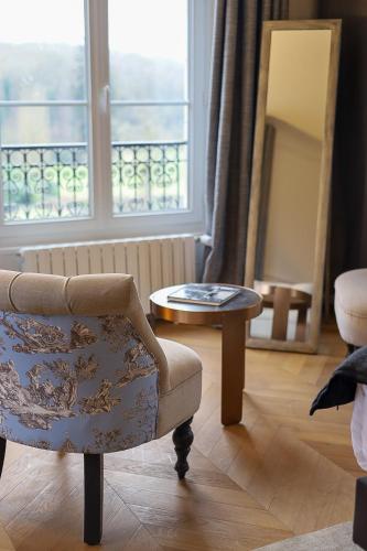 a living room with a chair and a table at Château De La Bûcherie in Saint-Cyr-en-Arthies