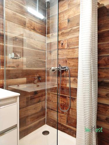 La salle de bains est pourvue d'une douche et de murs en bois. dans l'établissement La Casa Inès Creole charm direct lagoon access, à La Celle-sous-Gouzon