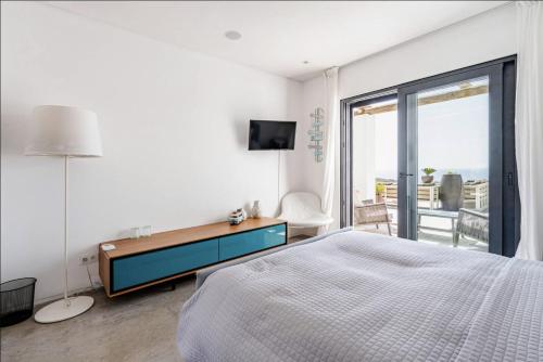 a bedroom with a bed and a desk and a balcony at Bica Vista in Lourinhã