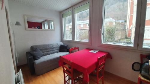 - un salon avec une table rouge et un canapé dans l'établissement Appartement rénové en plein coeur de Cauterets, à Cauterets
