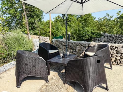 a table with four chairs and an umbrella at Holiday Home Little Heaven in Ivišovo Greblje