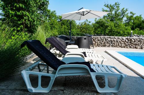 a group of lounge chairs and an umbrella next to a pool at Holiday Home Little Heaven in Ivišovo Greblje