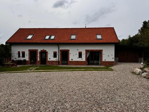 a white house with a red roof on a gravel driveway at Miejski Las 8 in Mrągowo