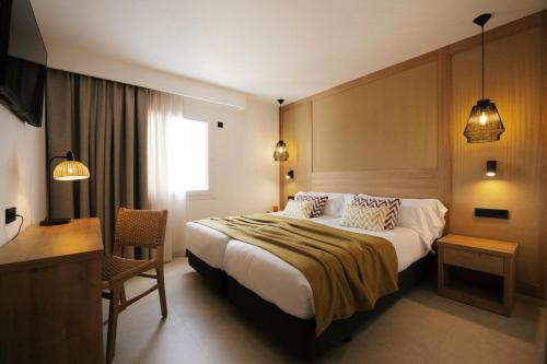 a hotel room with a large bed and a desk at Caramelo Marina Calan Bosch - Adults Only in Cala en Bosc