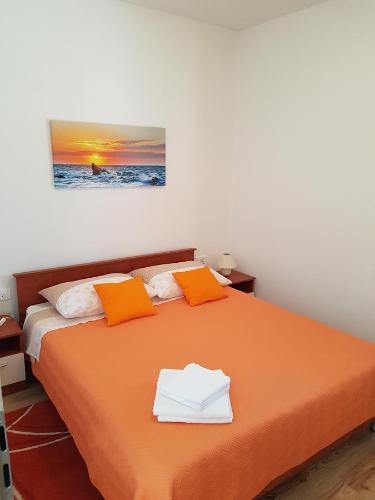 sypialnia z pomarańczowym łóżkiem z pomarańczowymi i białymi poduszkami w obiekcie Apartment Labin w mieście Labin