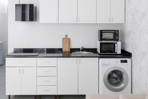 a kitchen with a washing machine and a microwave at Ro's Lil Suites San Juan Alicante in Alicante