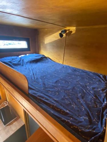 a bed with a blue sheet on top of a boat at Domek Surf Camp in Jastarnia