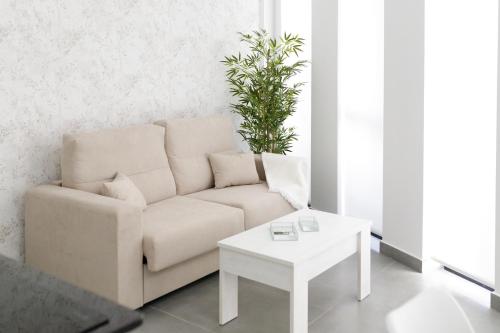 a living room with a couch and a table at Ro's Lil Suites San Juan Alicante in Alicante