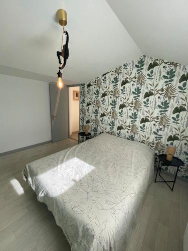 une chambre avec un lit et un mur avec du papier peint à fleurs dans l'établissement Lou Castelet maison de charme climatisée Centre ville Albi, à Albi