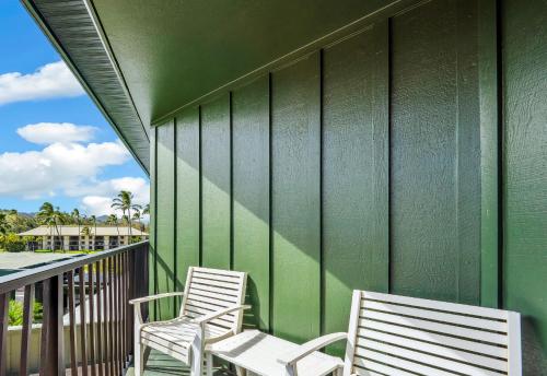 two chairs sitting on a balcony with a green wall at 2417 at Oceanfront Resort Lihue Kauai Beach Drive Private Condo in Lihue