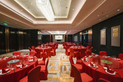 a conference room with red tables and chairs and a screen at The International Trade City, Yiwu - Marriott Executive Apartments in Yiwu
