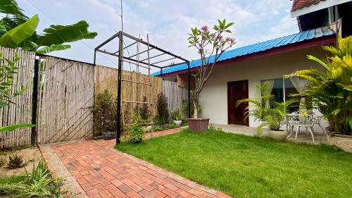 a garden with a brick walkway in front of a house at Cozy Paradise in Battambang