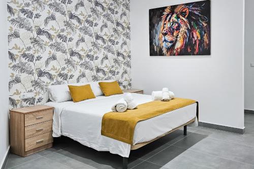 a bedroom with a bed with a painting on the wall at Ro's Lil Suites San Juan Alicante in Alicante