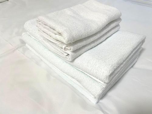 a stack of white towels sitting on a bed at Gest house Near Disneyland in Tokyo