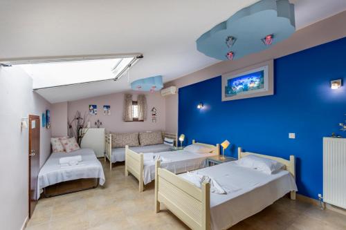 a room with three beds and a blue wall at Sofia's Villa in Nikiti