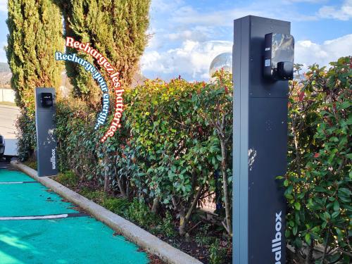 a parking meter next to a garden with a sign at ibis Budget Millau Viaduc in Millau