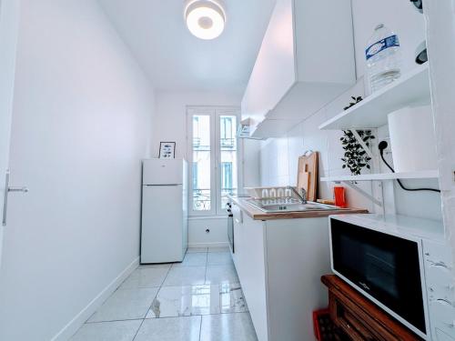 Il comprend une cuisine blanche équipée d'un réfrigérateur et une télévision. dans l'établissement Comfort et Style, Paris Stade de France, à Saint-Denis