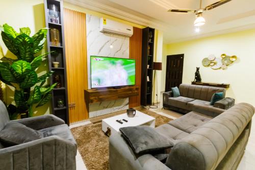a living room with two couches and a flat screen tv at Bawuah Royal Apartments in Kasi