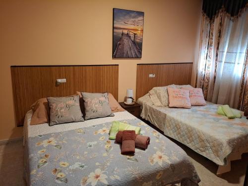two beds in a hotel room with a stuffed animal on them at Casa Rural & Parrillada Miguel in Lousame