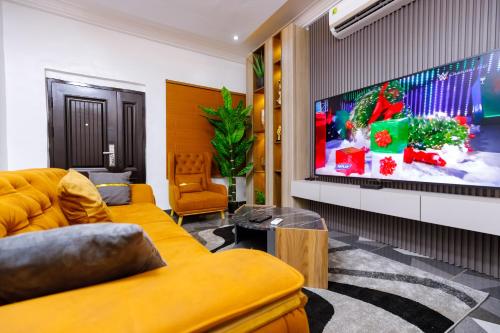 a living room with a yellow couch and a flat screen tv at Bawuah Royal Apartments in Kasi
