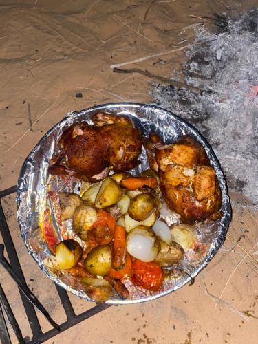 a chicken and vegetables in a pan on a table at وادي رم إبوفيصل in Wadi Rum