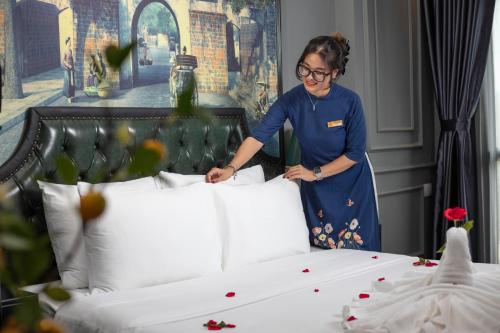 a woman is standing next to a bed at Hanoi View Hotel & Travel in Hanoi