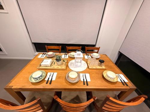 a wooden table with plates and silverware on it at Golden Palm Palace in Clyde North