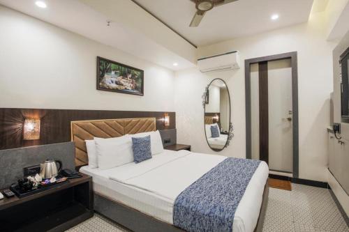 a bedroom with a large bed and a mirror at Rich Hotel in Mumbai