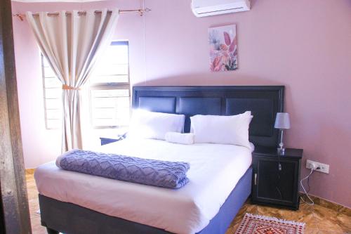 a bedroom with a large bed and a window at Masiyabundu Guest House in Gaborone