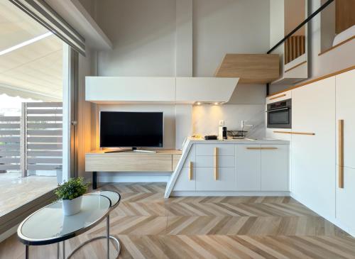 a kitchen with white cabinets and a tv and a table at Luxury Downtown Apartment With Seaview E2 in Thessaloniki