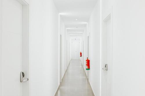 a hallway with white doors and a red fire extinguisher at Ro's Lil Suites San Juan Alicante in Alicante