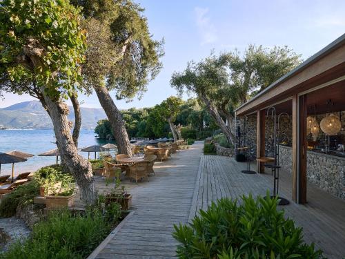 a wooden walkway with tables and chairs next to the water at Grecotel Eva Palace in Kommeno