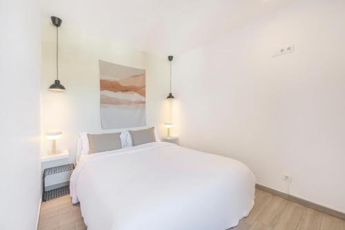 a white bedroom with a white bed and two lamps at Equador Studios by Olala Homes in Cascais