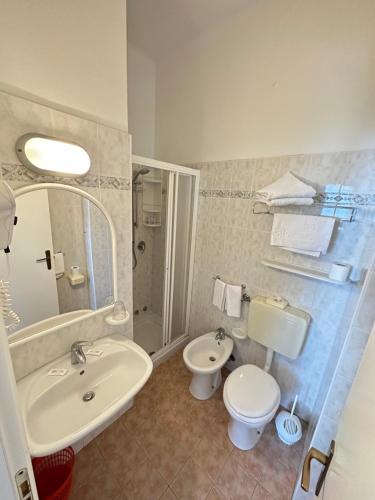 ein Badezimmer mit Waschbecken, Toilette und Spiegel in der Unterkunft Hotel Fiorenza in Milano Marittima