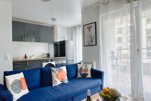 un salon avec un canapé bleu et une cuisine dans l'établissement Appartement Chic, à Saint-Ouen