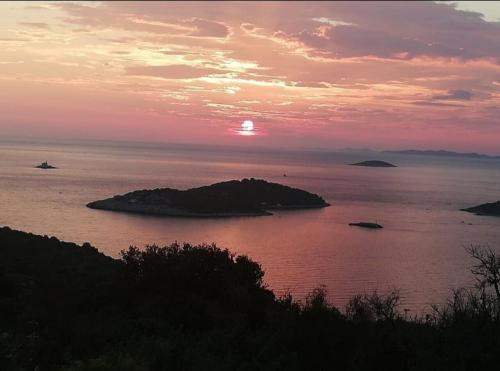 a sunset over a body of water with an island at 3 bedroom Apartment on the sea with garden in Ražanj