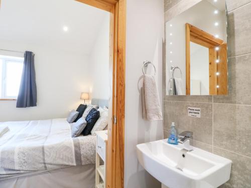 a bathroom with a sink and a bed and a mirror at Mandarin Cottage in Melton Mowbray