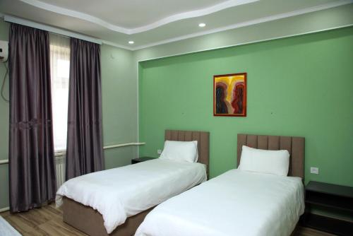 two beds in a room with green walls at Travel Point hotel in Bishkek