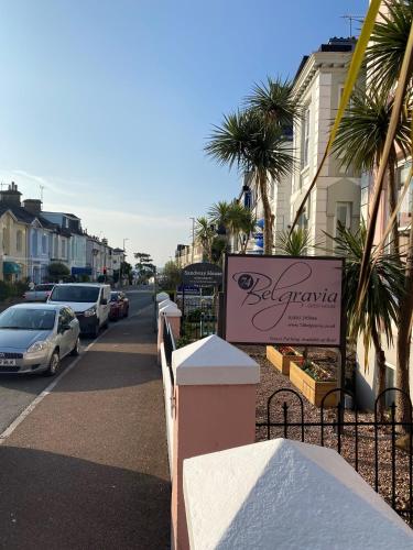 a sign for a restaurant on a street with parked cars at 74Belgravia in Torquay
